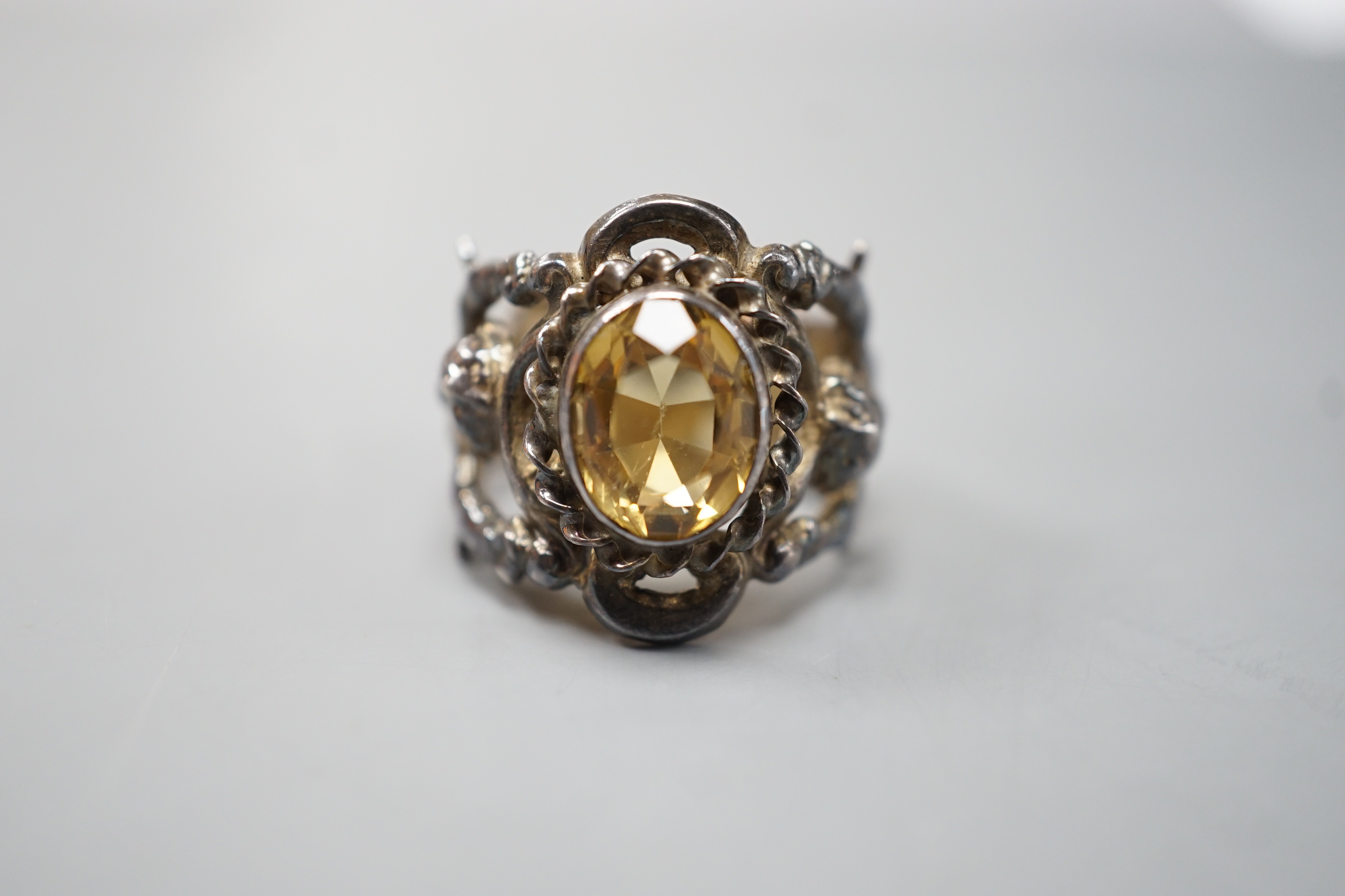 A 1960's silver and oval cut citrine set ring, the shank modelled and twin cupids, size O, gross weight 9.2 grams.